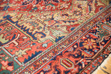 Vintage Heriz carpet showing even wear, with cherry red, deep blue, gold traditional motifs.