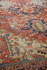 Vintage Heriz rug close-up: worn cherry red, sky blue, and saffron yellow geometric patterns.