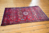 Vintage Lilihan rug corner: deep cherry red, geometric floral motifs, indigo blue, and isolated wear.