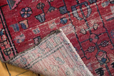 Cherry red hand-knotted Lilihan rug corner reveals geometric motifs and woven foundation.