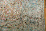 Corner of distressed Meshed rug, showing faded terra cotta and pastel floral patterns.