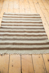 Hand woven fringe and natural striped texture on a neutral Moroccan Kilim rug.
