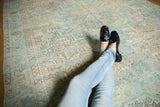 Close-up of distressed vintage Heriz rug, geometric pattern in sea foam green and beige.