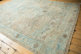 Distressed Heriz carpet border featuring geometric patterns in sea foam blue and coffee brown.