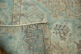 Distressed vintage Heriz rug, folded, revealing soft seafoam green pile and geometric foundation.