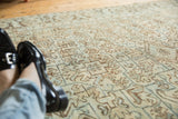Distressed vintage Heriz rug showcasing geometric floral lattice in pale sea foam and ivory tones.