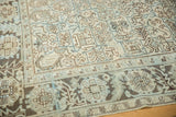 Distressed Heriz carpet close-up: geometric field and floral border in sea foam and ivory.