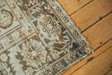 Distressed vintage Heriz carpet corner showcasing geometric floral motifs in pale sea foam green.