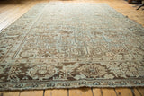 Angled view of the distressed Heriz rug showing rectilinear motifs and large floral border.