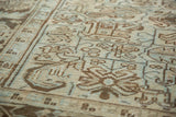 Distressed vintage Heriz rug detail: softened rectilinear geometric patterns in beige and pale seafoam.