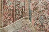 Distressed blush and blue floral pile with visible woven foundation of a Hamadan rug.