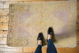 Distressed vintage Oushak rug with faded saffron yellow and lavender hues underfoot.