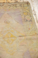 Distressed Oushak rug detail: worn texture, exposed foundation, saffron, lavender colors.