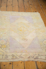 Distressed vintage Oushak rug's lower edge with visible foundation, showing muted saffron and lavender.