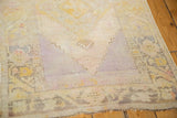 Distressed vintage Oushak rug corner, worn texture with lavender and saffron yellow.