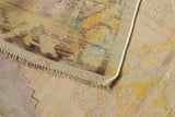 Distressed Oushak rug corner showing wear, exposed foundation, and color migration on reverse.