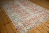 Distressed vintage Heriz carpet section, geometric vines in pale cranberry and faded teal.