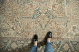 Feet on distressed Mehrivan rug, highlighting faded geometric design and main border detail.