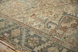 Distressed vintage Mehrivan rug showcasing faded beige and dusty teal geometric floral motifs with border.