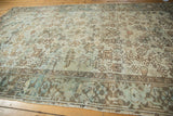 Distressed Mehrivan carpet displaying geometric plant designs and abashes in soft blue and brown.