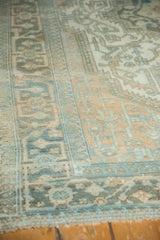 Distressed Malayer carpet displaying geometric border patterns in pale gold and powder blue.