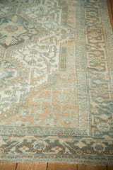 Distressed Malayer carpet corner detail, displaying muted ivory, blue, and copper geometric patterns and fringe.