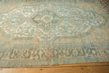 Distressed Malayer rug texture: low pile, faded geometric blue and gold patterns, scattered white knots.