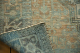 Distressed low pile of Malayer carpet in muted teal and gold, revealing woven back and fringe.