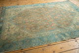 Distressed aqua border with budded floral lattice details on a vintage Persian rug.