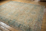 Distressed Persian Karaja carpet featuring faded multi-medallion design in sand, dusty teal, and rose.