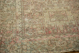 Decorative distressed Karaja rug corner, revealing soft ivory, blush, and sand geometric motifs.