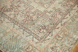Distressed Karaja rug corner showing rectilinear geometric patterns in ivory, blush, and powder blue.