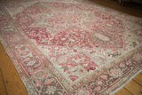 Distressed Heriz carpet with raspberry red, antique ivory, and pale blue geometric floral patterns.