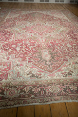 Heriz carpet border's distressed pile texture, with faded raspberry and ivory geometric patterns.