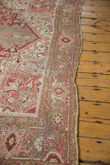 Distressed edge of a vintage Heriz carpet showing softened raspberry, blush, and ivory floral patterns.