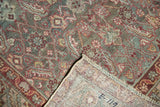 Distressed Malayer rug runner corner revealing its hand-knotted foundation, fringe, and muted Herati pattern.