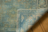 Folded corner of distressed Karaja runner, revealing fringe and blue-gold hand-knotted foundation.