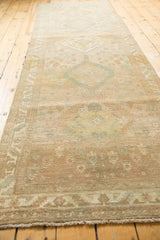 Distressed Serab runner end detail: worn pile, secured fringe, muted beige and seafoam green colors.