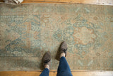Distressed vintage Heriz rug runner with worn knots and faded teal, beige tones.