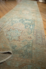 Worn distressed pile of vintage Heriz runner in faded teal, beige, bronze tones.