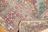 Distressed Oushak rug corner showing geometric patterns, fringe, even wear, and hand-knotted foundation.