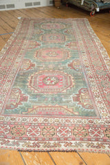 Faded raspberry red and ivory geometric border with secured fringe on a distressed Oushak rug.