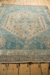 Secured fringe and textured geometric border of the distressed vintage Afshar rug in aqua and sand.