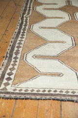 Gabbeh rug's side, featuring small diamond inner border, faded copper brown, and charcoal fringe.