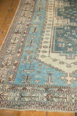 Distressed Sirjan rug detail: aqua blue field, geometric motifs, worn low pile, brown border.