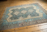 Distressed vintage Sirjan rug's geometric border and textured aqua blue field, with blush hints.