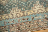 Distressed Sirjan rug detail: aqua, ivory, and brown geometric borders with pinwheels.