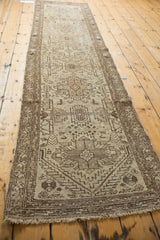Distressed vintage Hamadan runner end, with worn fringe and ivory-brown geometric patterns.