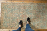 Distressed Vintage Borchalou rug corner, low pile with faded peachy blush, sky blue motifs.