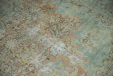 Distressed pile of a vintage Heriz carpet showing faded apricot, powder blue floral motifs.